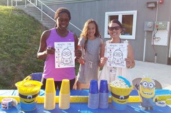 Crystal Run Healthcare Pediatricians, Dr. Jocelyn Dummett (left) and Dr. Lin-Lin Remenar (right), and Sydney Remenar (center) pose for a picture in front of the welcome table with a ‘Healthy Tips’ handout, at Friday night’s event.  