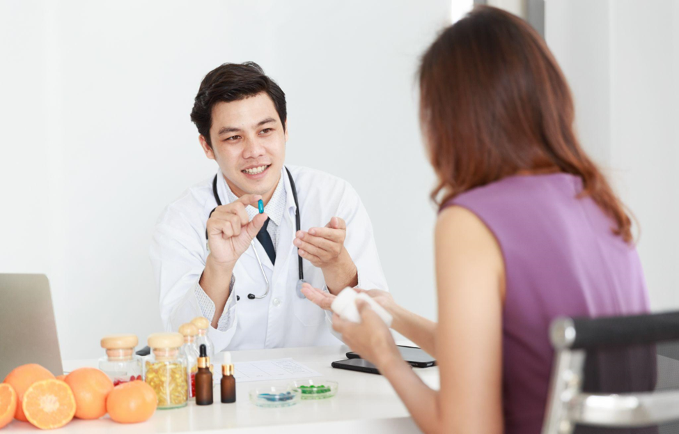 Asian male professional nutrition holding supplement pill explaining weight loss decision choice to female patient