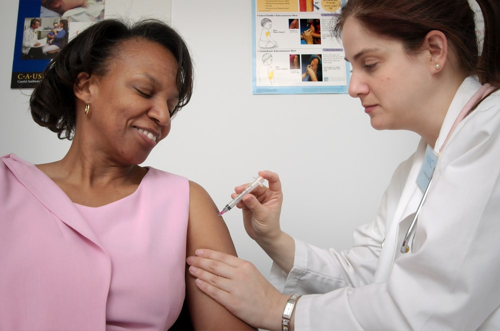 doctor administering vaccine to woman