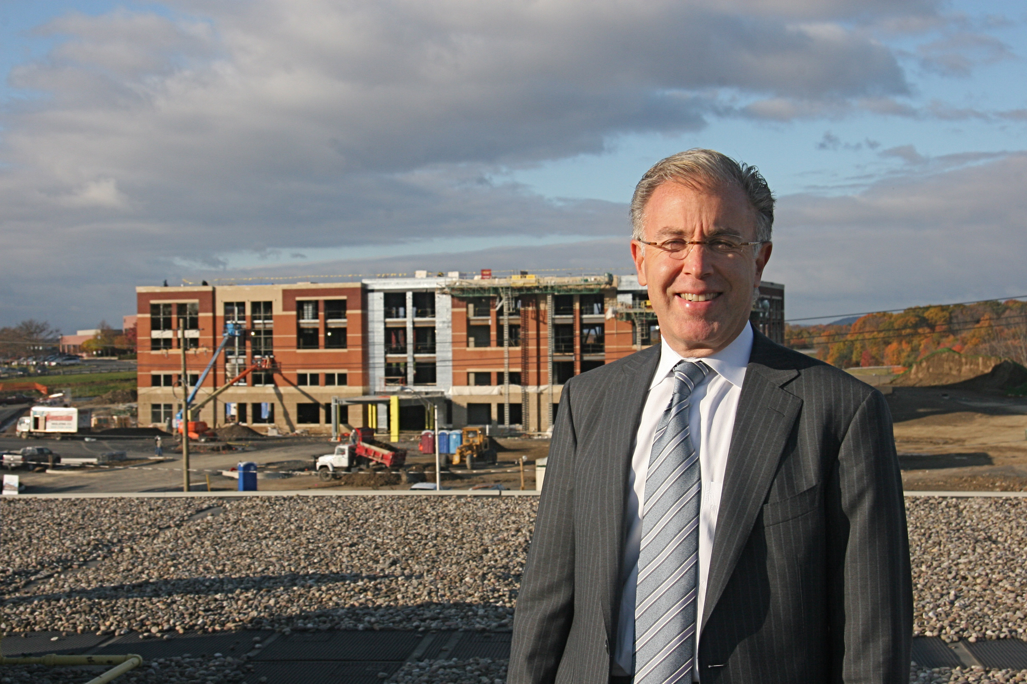 Dr. T facing camera smiling on roof with crystal run healthcare building behind him