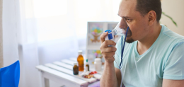 a sick man breathes through an inhaler mask