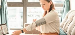 A person monitors their blood pressure during a virtual visit with a provider