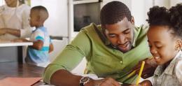 Father and daughter doing homework in kitchen