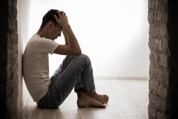 young-man-sitting-on-a-floo-with-hands-on-head