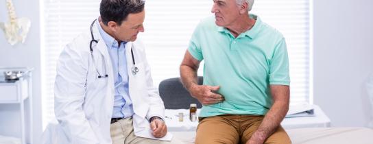 senior-man-showing-stomach-pain-to-doctor