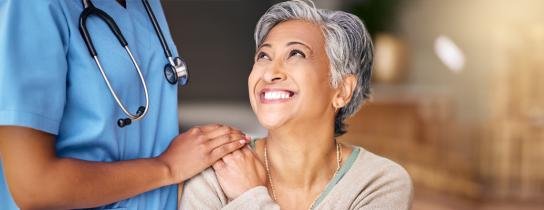 Healthcare provider's caring hand on smiling patient's shoulder
