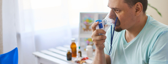 a sick man breathes through an inhaler mask